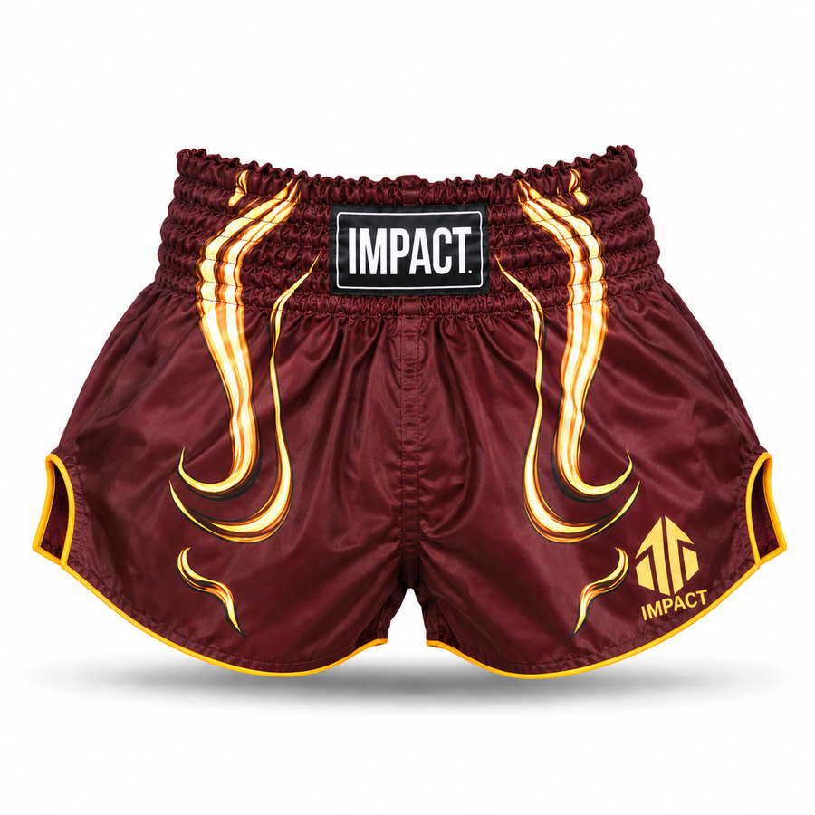 Burgundy and gold IMPACT Muay Thai shorts with curved high-cut hems and centered IMPACT waistband patch