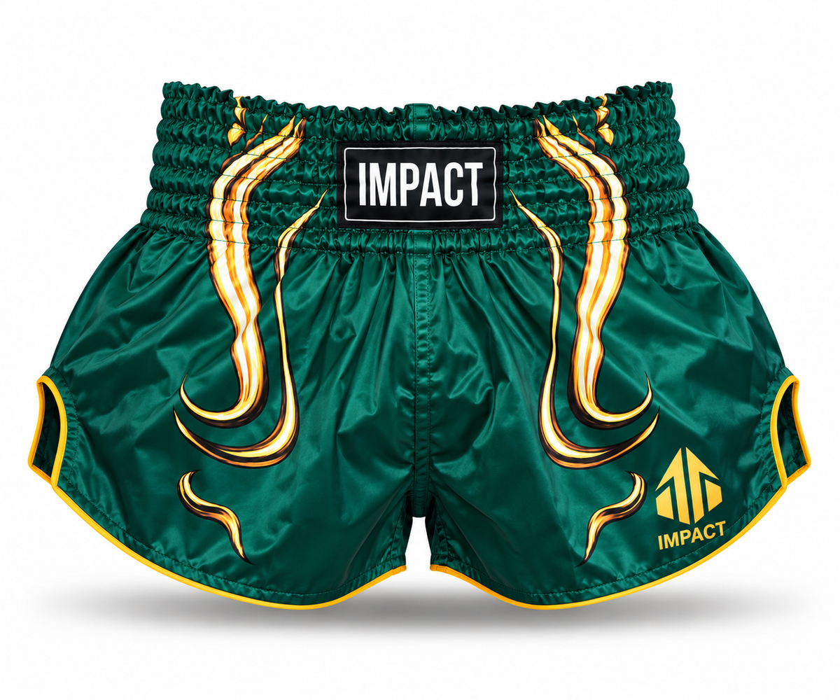 Green and gold IMPACT Muay Thai shorts with traditional curved high-cut hems and IMPACT waistband patch