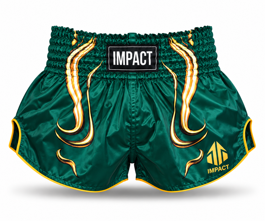 Green and gold IMPACT Muay Thai shorts with traditional curved high-cut hems and IMPACT waistband patch
